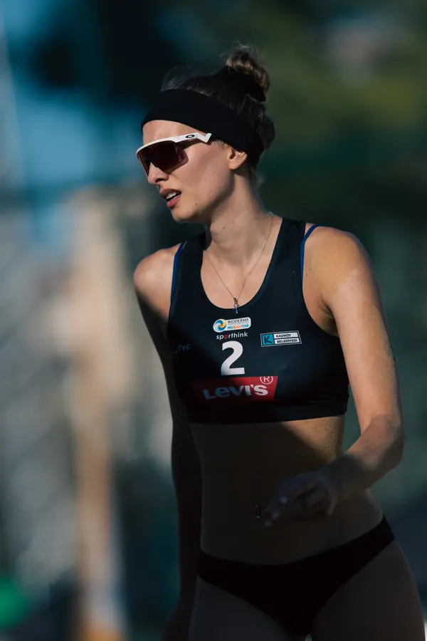 Portrait of a beach volleyball player in a black kit, number 2, looking across the court