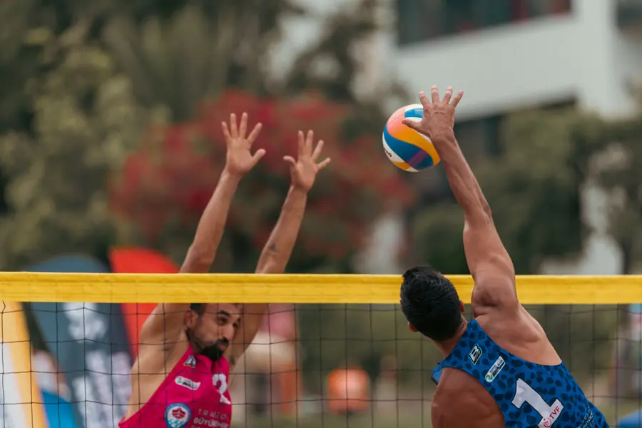 Two blockers reach over the net for the ball